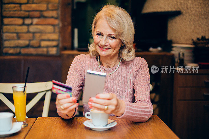 在咖啡厅网上购物的快乐成熟女人