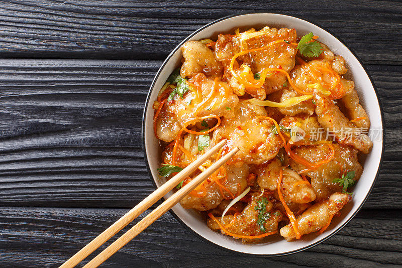 中国糖醋猪肉与胡萝卜，洋葱，大蒜和生姜在碗里特写。水平的俯视图