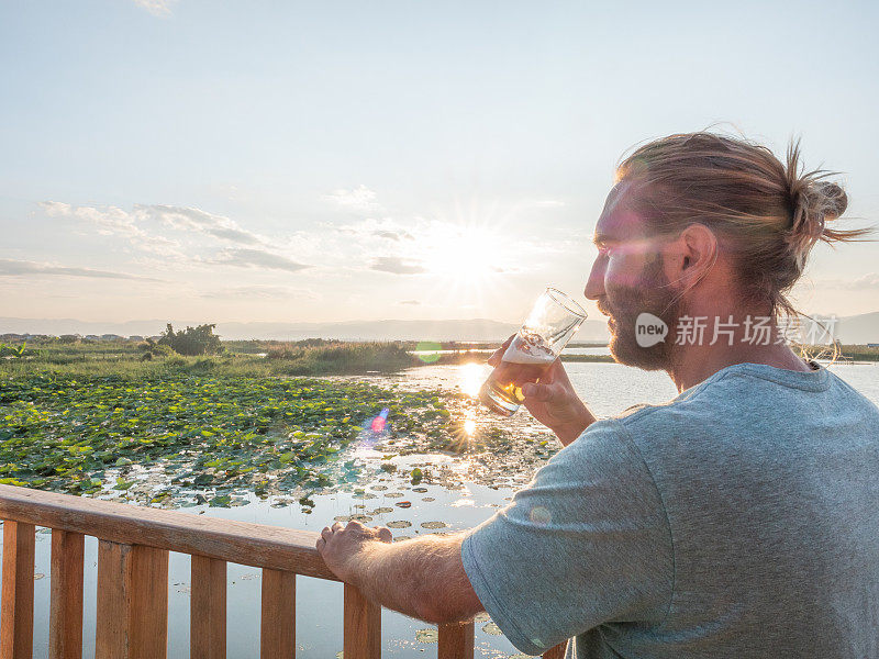 一个男人一边喝着饮料一边看日落