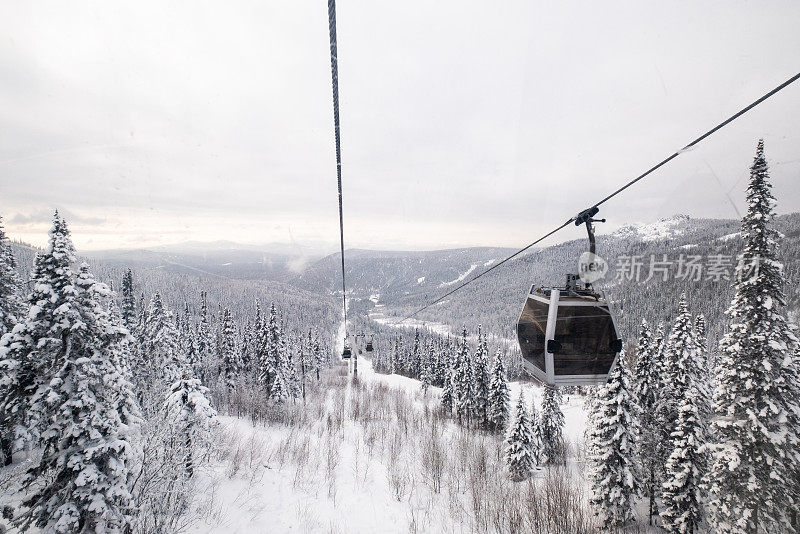 缆车在滑雪胜地的雪覆盖的斜坡上，冬天的树木，山上的景观