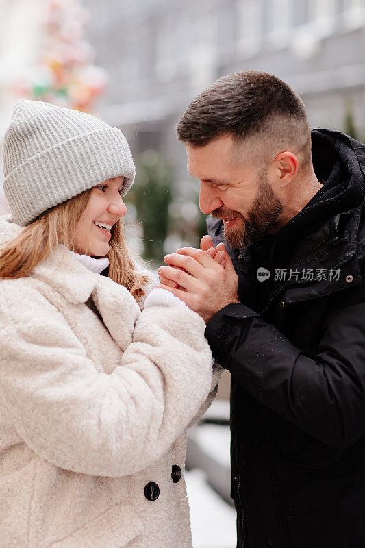 爸爸和女儿走在冬天的街道上，用呼吸温暖她的手。
