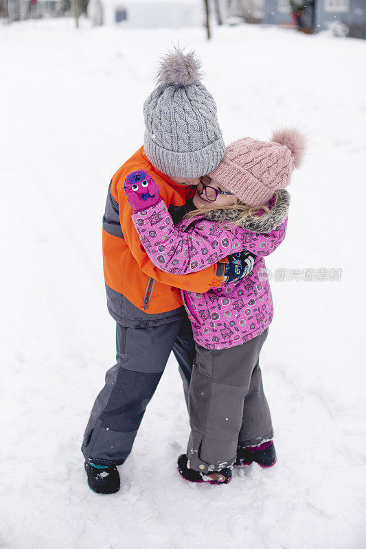 两个孩子在雪地里拥抱玩耍