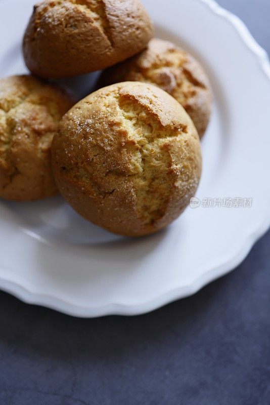 白色陶瓷盘子上的大圆橙饼干，以深灰色的石头为背景，茶和咖啡时间，特写