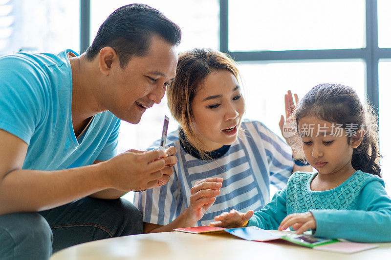 年轻的混血亚洲家庭与宝丽来即时照片在家。