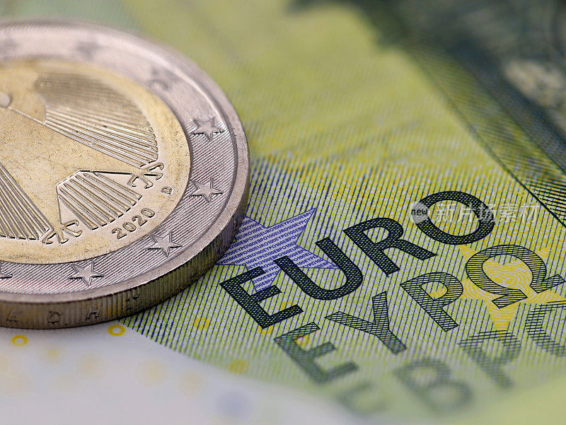 欧元纸币与硬币的特写，选择性聚焦于“欧元”这个词