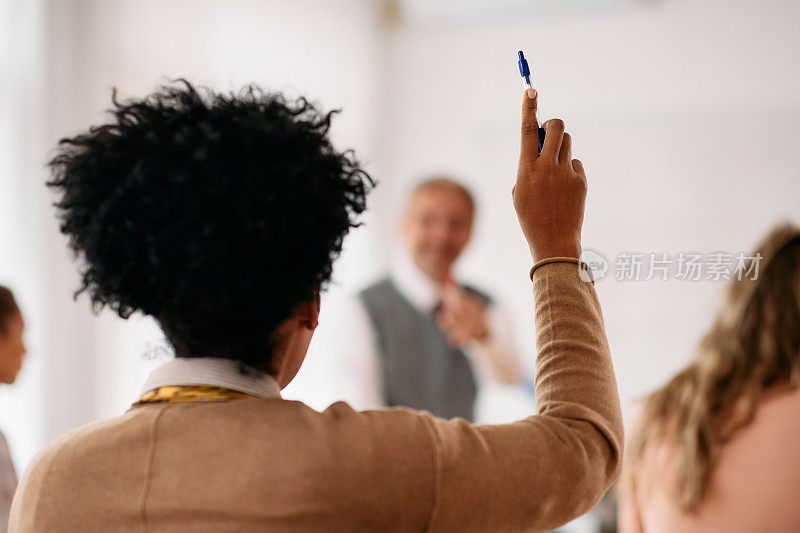 非裔美国学生在课堂上举手回答问题的后视图。