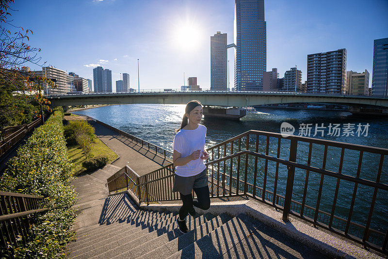 一个女人在城市的河边慢跑