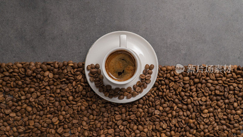 这张照片一半是用咖啡豆做的，另一半是空白的。在中间，有一个装满土耳其咖啡的咖啡杯。这张照片给人一种几何和和谐的感觉。这款咖啡，咖啡豆，咖啡杯，饮料的概念。