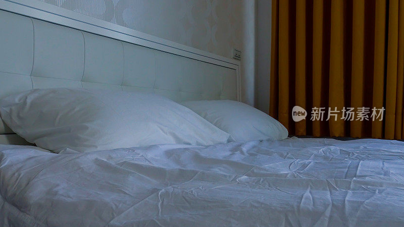 酒店房间里的双人床，白色褶皱床单