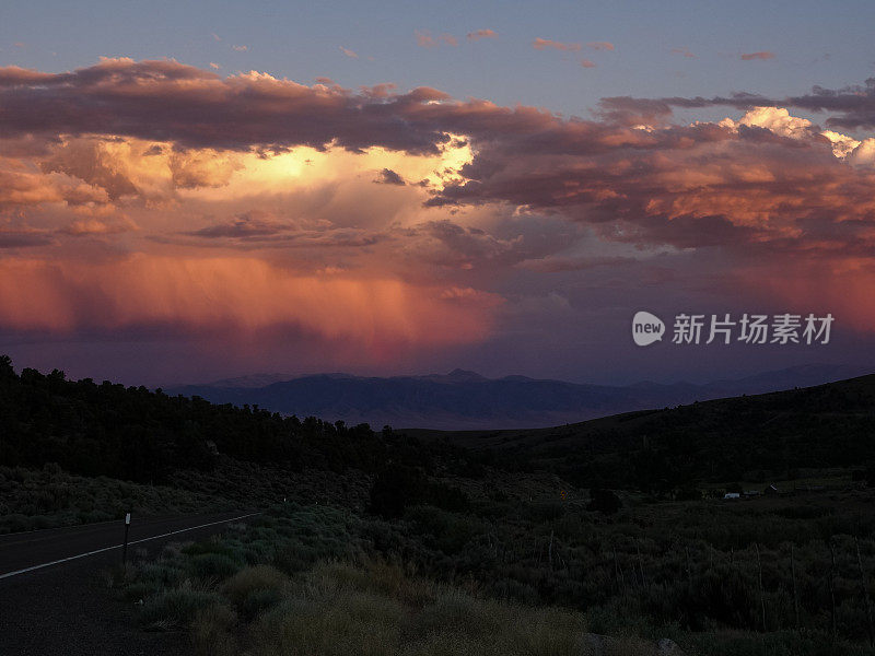 远处明亮的橙色暴风云笼罩着黑暗的沙漠山谷