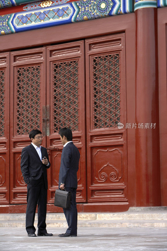 两位商务男士在太庙前说话