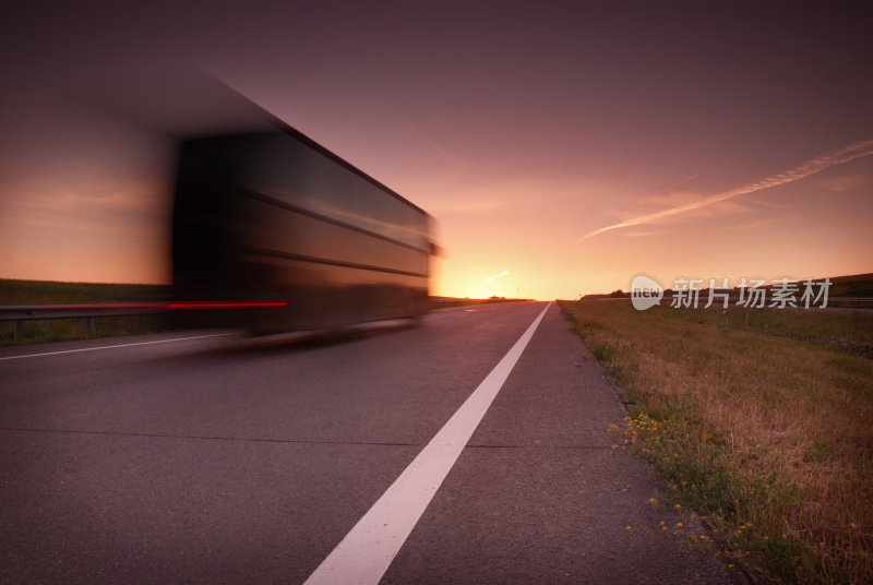 夕阳下高速公路上模糊的半卡车