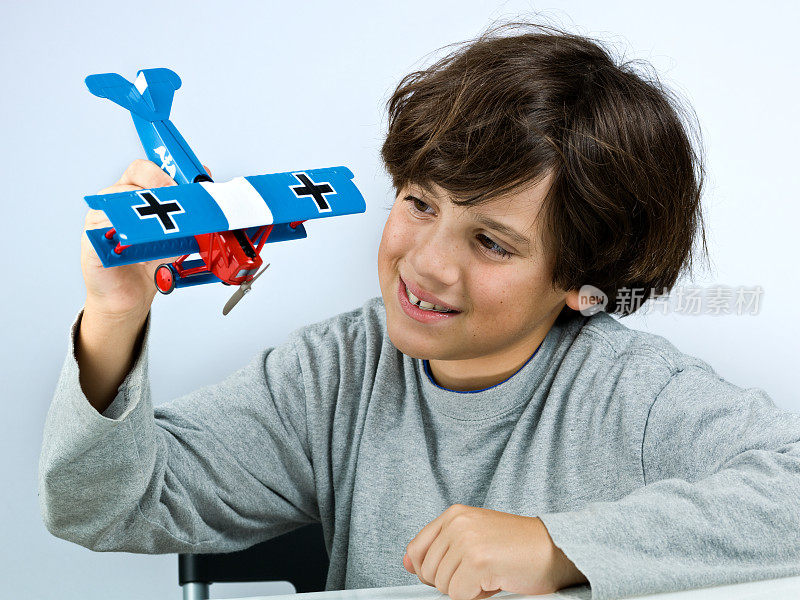 一个小男孩在玩一架蓝色的玩具飞机