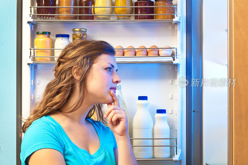 在打开冰箱的深夜里琢磨着吃夜宵的女人