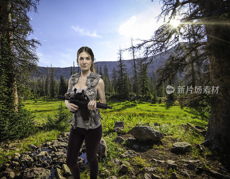 拿着突击步枪在森林里打猎的女人