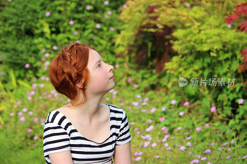 年轻的女孩在夏日的花园里做白日梦，向上看