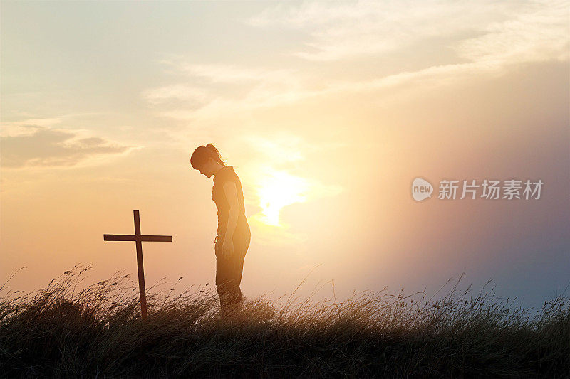 在夕阳背景下的田野上，女人尊重着十字架