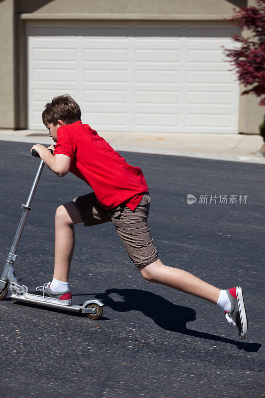 男孩推着滑板车上山