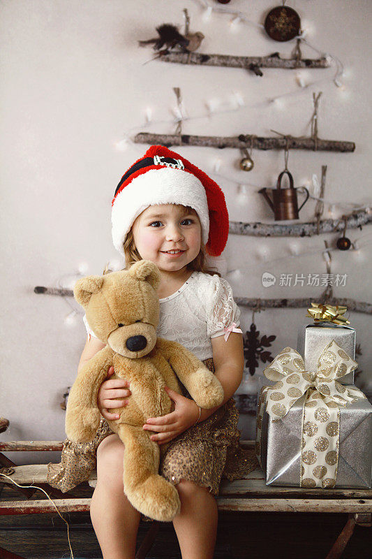 圣诞树旁带着泰迪熊的孩子