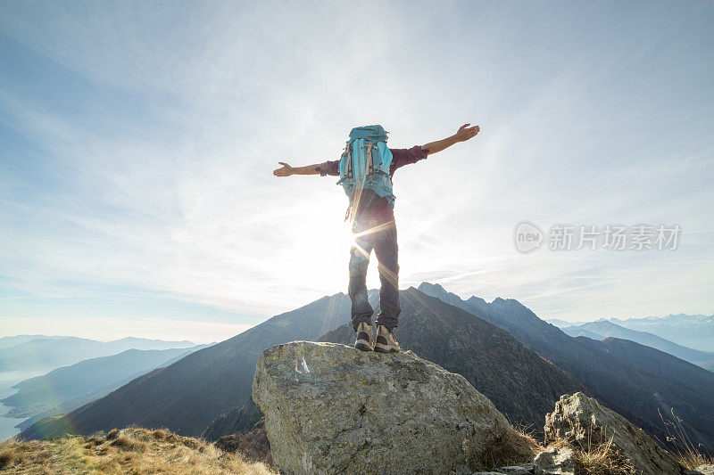 徒步旅行者向夕阳、群山伸展双臂