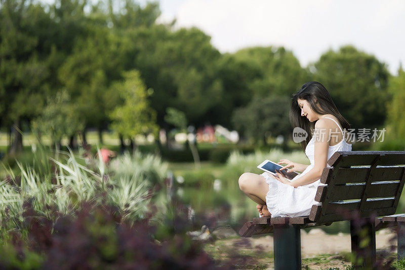 年轻女子在公园里使用数字平板电脑