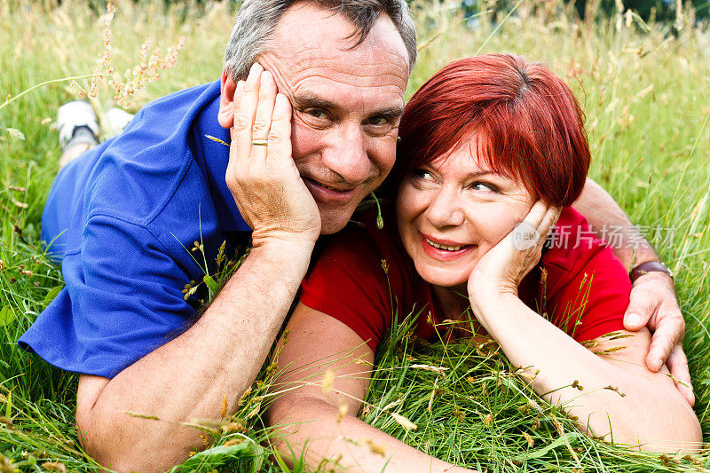 幸福成熟的夫妇躺在草地上拥抱，肖像