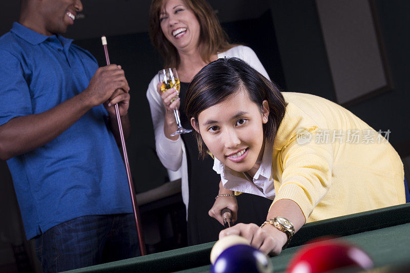 年轻的亚洲女人在台球馆里和朋友打台球