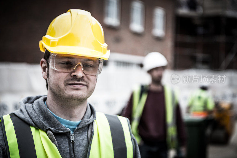 年轻建筑工人戴安全帽在建筑工地