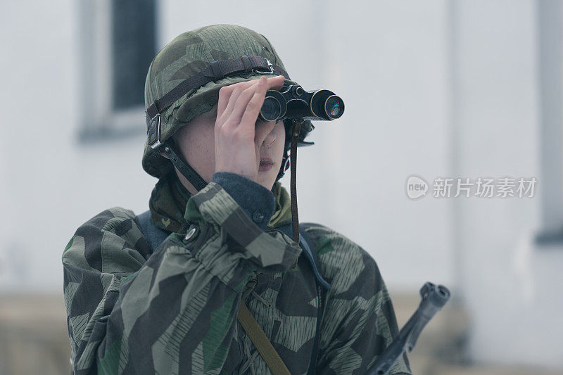 在射击场上用双筒望远镜观察目标的士兵