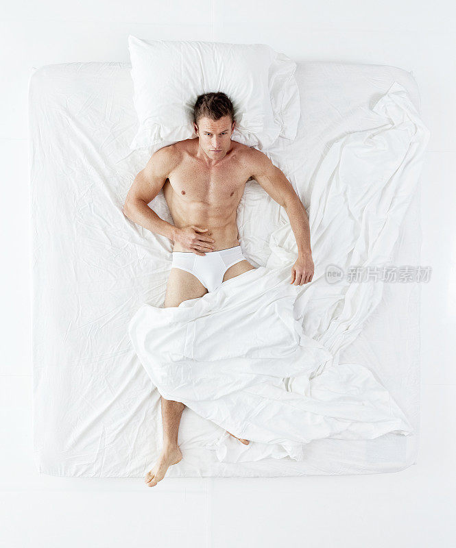 上图是一个肌肉发达的男人躺在床上