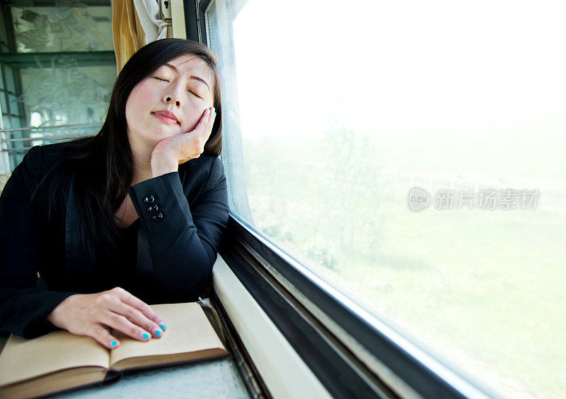 年轻女商人在火车上看书时睡着了