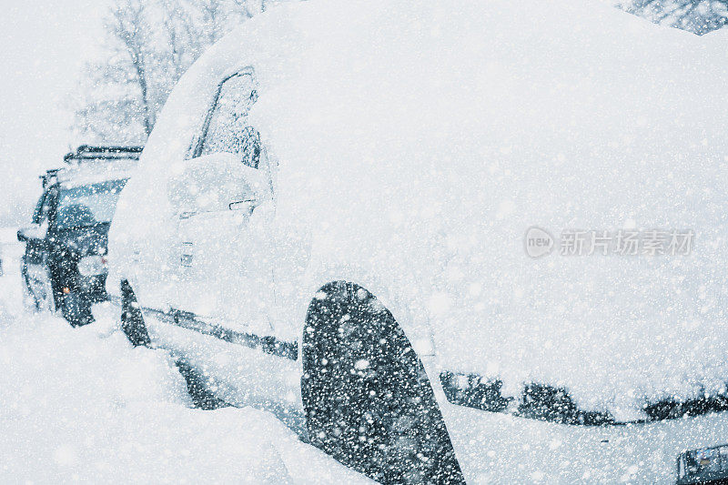 在一场暴风雪中，雪覆盖了停放的汽车