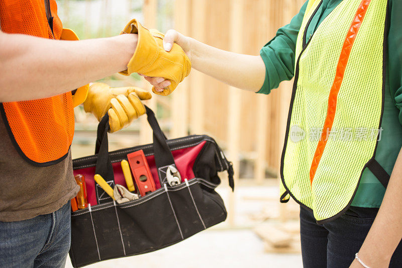 建筑工人在建筑工地握手。