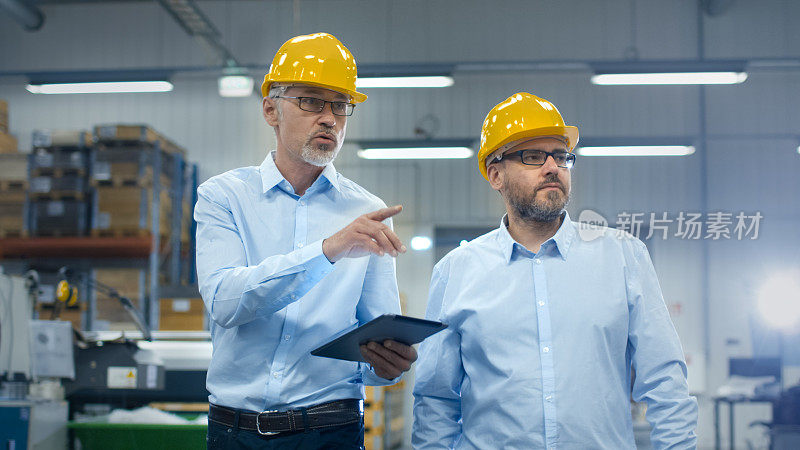 在物流中心的仓库里，两名员工手持平板电脑。
