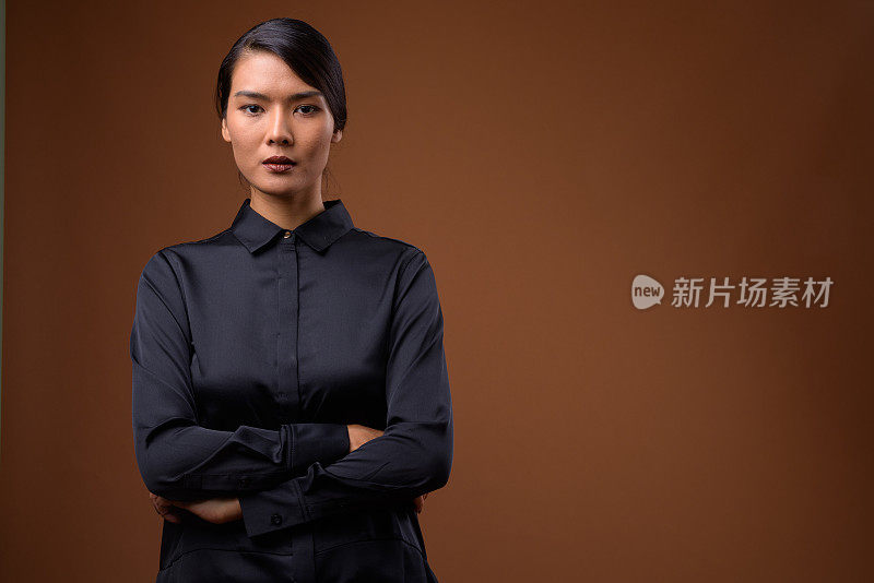 工作室拍摄的美丽的亚洲女商人穿着黑色丝绸衬衫，以彩色背景