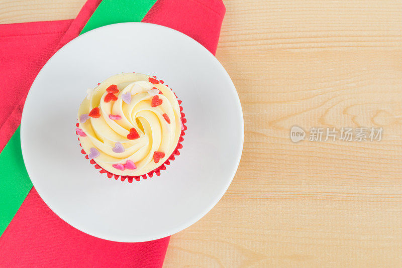 红丝绒杯型蛋糕，白色的盘子和红色的餐垫与绿色的圣诞丝带在木板和复制空间插入文本在圣诞节，新年，情人节或特别的节日庆祝