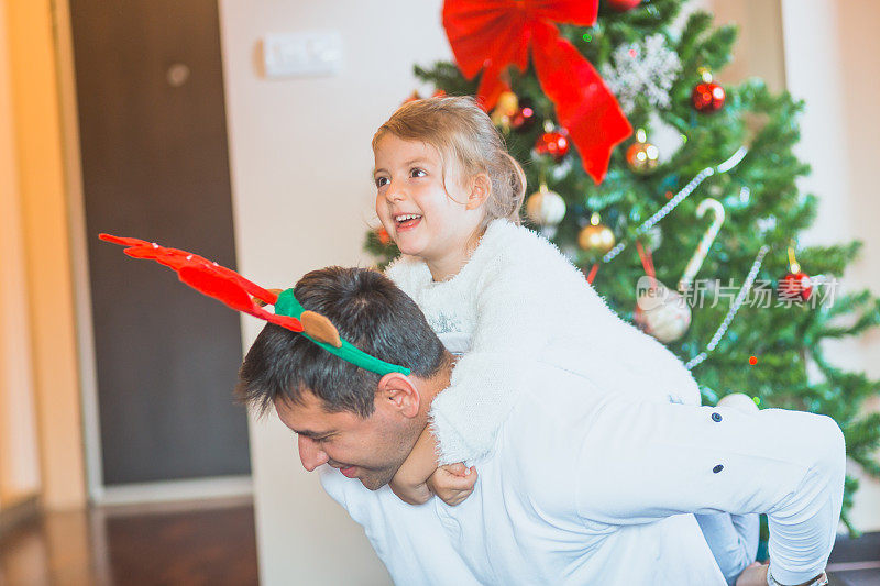 圣诞节。可爱的小女孩和她的爸爸在他们家的圣诞树前玩耍