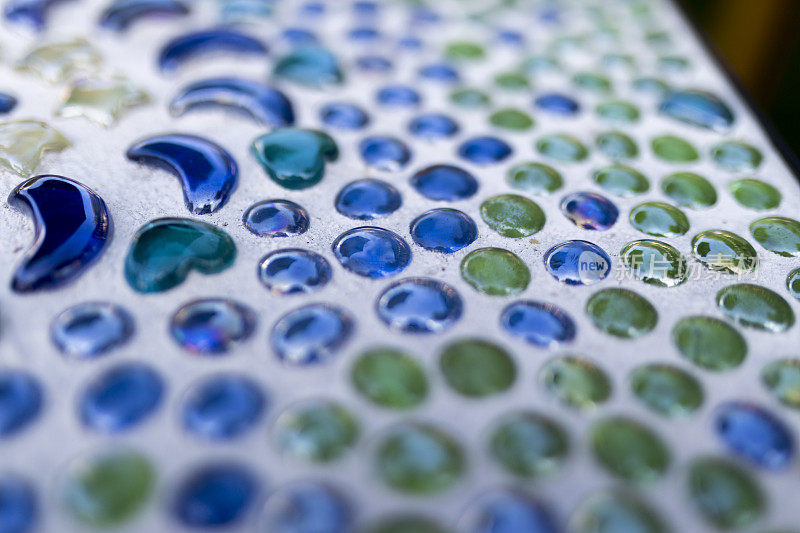 蓝色和绿色美丽的装饰玻璃珠粘在桌面上