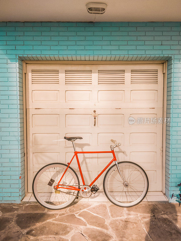 固定齿轮的自行车没有刹车支撑在车库门上，随时准备去散步，复古复古的风格。