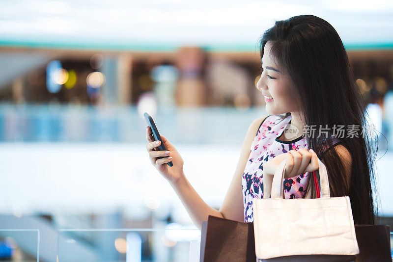 亚洲女性购物中心的购买力快乐。她的手机店