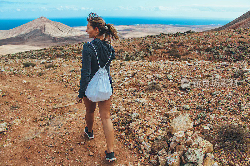 年轻女子徒步旅行与全景火山