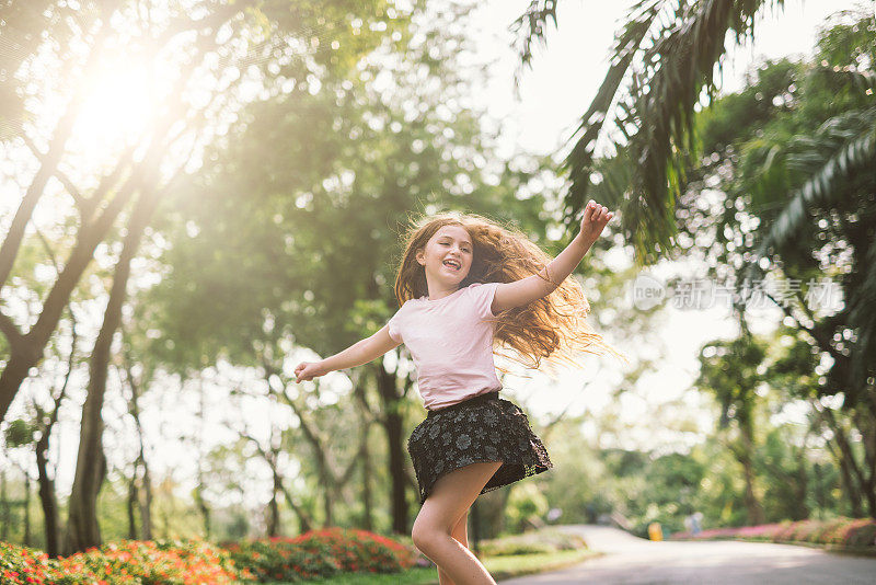 年轻的女孩张开双臂享受她的自由，在公园如此快乐放松的舞蹈