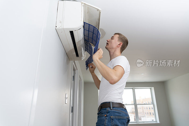 在最近租来的公寓里，清理空调分离装置过滤器的年轻人