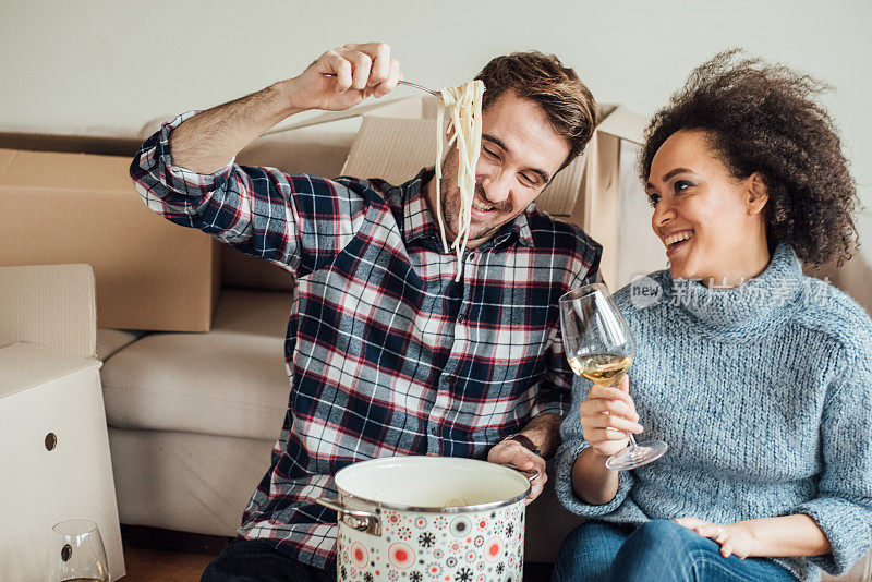 一对幸福的情侣在新公寓里吃意大利面喝葡萄酒