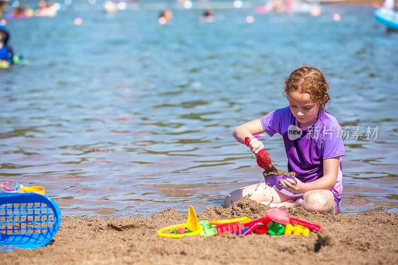 小女孩在沙滩上玩沙子和水