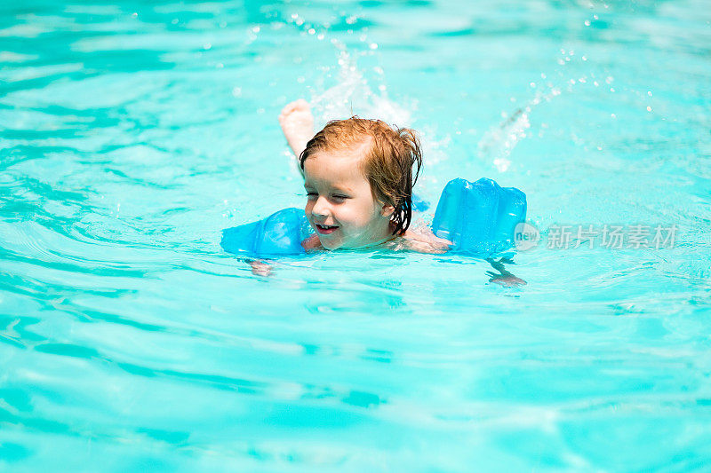 可爱的男孩在游泳池里游泳