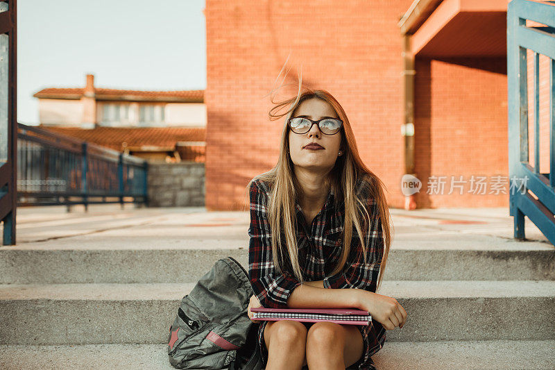 一个美丽的少女坐在教学楼前的肖像