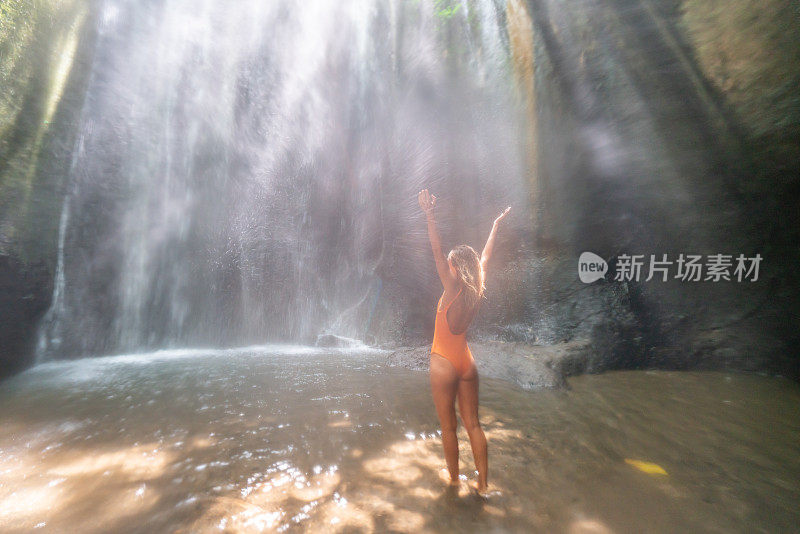 在巴厘岛的热带雨林中，旅行的年轻女子张开双臂拥抱大自然的美丽。人们以自然为旅游理念。