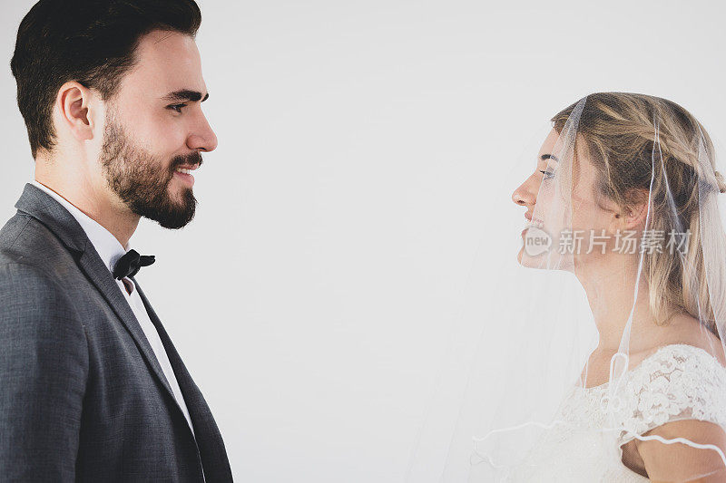 年轻的情侣穿着婚纱站在一起，深情地看着对方