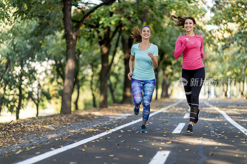 两个女性朋友在阳光公园的小路上慢跑